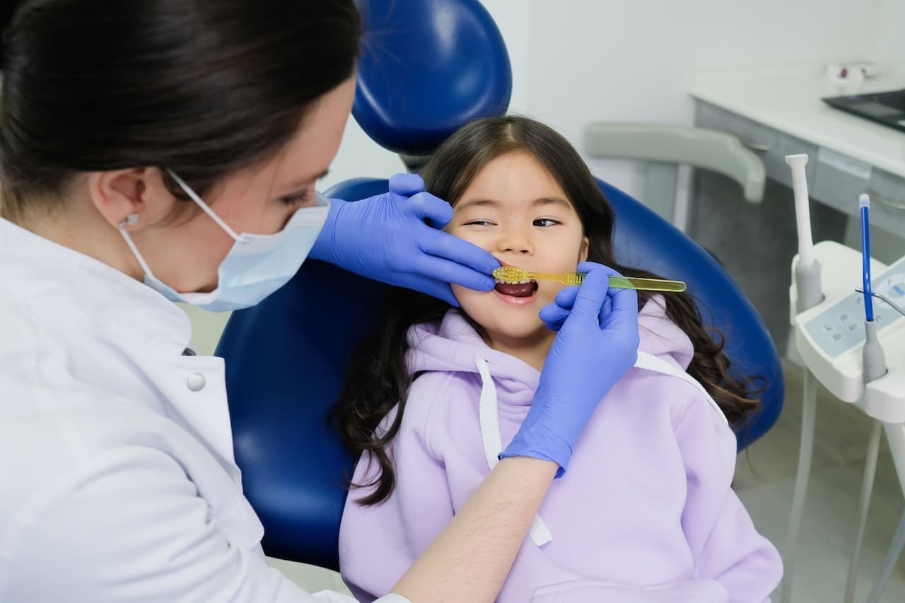 Dentist instructing child on how to brush teeth